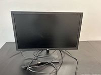 Front view of LG 24-inch computer monitor on a black surface with power and HDMI cables.