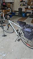 Full view of Raleigh Summit 1 silver mountain bike with rear rack and cooler bag mounted, in garage setting.