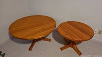Top view of two round pine coffee tables, showing wood grain and pedestal base with four legs each.