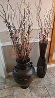 Photo of two decorative vases with natural branches, showing the overall arrangement and setting.