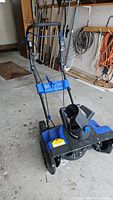 Front angled view of blue and black Snow Joe electric snow blower, showing handle and chute.