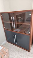 Full view of the wooden entertainment unit with glass upper doors and solid lower doors.