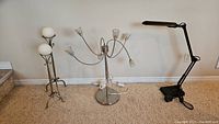 Three lamps placed side by side: a multi-headed piano lamp on a round base, and two decorative lamps with white sphere bulbs on metal stands.