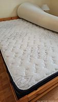 Mattress and pine bed frame with memory foam topper partially rolled