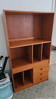 Front view of the complete modular teak cabinet showing open shelving, drawers, and dividers.