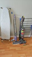 Front view of entire lot showing ironing board, mop/steamer, vacuum, and laundry rack against wall on floor