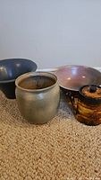 All four pottery pieces grouped together: three bowls and one small coffee/tea pot, shown on carpeted floor.