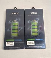 Front view of two sealed DEJI iPhone X replacement battery packages showing brand, capacity, and model info.