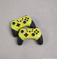 Two yellow and black wireless Nintendo Switch game controllers with blue accents placed on a table, front side showing buttons and joysticks.