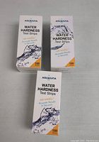 Front view of the three boxes of Aququina Water Hardness Test Strips showing brand, usage instructions, and quantity (100 strips each).