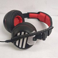 Black and red Bluetooth over-ear headphones with padded earcups and headband, visible grille design and microphone boom.