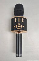 Black and gold wireless Bluetooth microphone with integrated speaker and control buttons on the body.