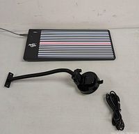 LED-powered paintless dent repair reflector board, flexible arm with suction cup, and cable on a table