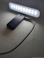 Portable LED desk lamp lit up connected by USB Type cable showing brightness and lighting function on a white surface.