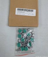 Plastic bag containing 10 green and silver potentiometers with metal shafts, displayed on a brown cardboard surface.