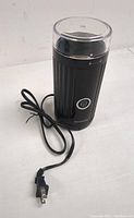 Full view of Shardor electric coffee grinder with power cord and transparent lid on top, showing black body with ridges and brand name near base.