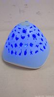 White triangular solar pool light with blue LED fish and sea creature patterns illuminated from inside