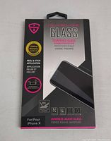 Front of the black and gray packaging box for iShieldz tempered glass screen protector showing product name, phone model compatibility, peel & stick application, lifetime warranty, and Japanese Asahi glass mention