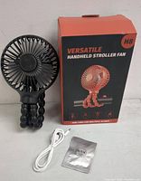 Photo of black handheld flexible stroller fan with USB charging cable and user manual alongside original packaging box showing image and brand info.