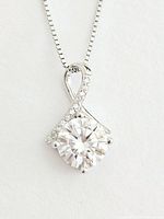 Close-up view of twisted silver pendant with round moissanite stone showing detailed design and sparkle.