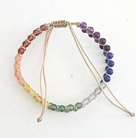 Full view of the bracelet showing all seven colored chakra beads arranged in a semi-circle on an adjustable beige cord.