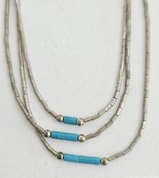 Close-up of the middle section of the 3-strand necklace showing silver tube beads and cylindrical turquoise beads separated by small round silver beads.