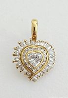 Front view of gold tone 925 marked heart pendant with clear CZ heart centerpiece and baguette and marquise CZ surrounding.
