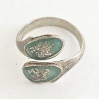 Close-up image of the adjustable sterling silver ring showing green enamel and silver-tone Siam-style motifs on each end of the band.