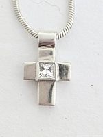 Close-up front of sterling silver cross pendant with prince-cut diamond in center