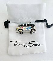 VW flower bus charm on a white Thomas Sabo branded pouch showing front side decorated with colorful enamel flowers, hearts, and peace sign.