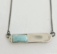 Front view of the rectangular silver bar pendant showing the turquoise stone inlay and chain attachments.