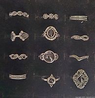 Photo of 12 assorted silver-tone fashion rings with black stones or black accents on display surface