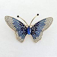Front view of butterfly rhinestone brooch showing gradient of blue, black, and clear rhinestones with gold-tone metal base.