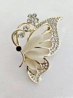 Front view of the butterfly brooch showing gold-tone metal, clear rhinestones, and frosted wings