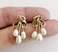 Both pierced earrings shown together with cultured pearls suspended from artistic gold-tone metal design.