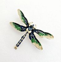 Front view of the dragonfly brooch showing detailed green and blue enamel decoration on wings and body.