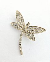 Front view of the dragonfly brooch showing gold tone body and wings covered with clear rhinestones.