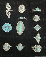 Top down view of 12 pre-owned Southwest style rings with turquoise stones arranged on black felt background showing varying shapes and designs.