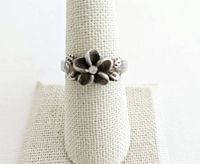Front view of a sterling silver ring with a raised three-dimensional flower design on the band.