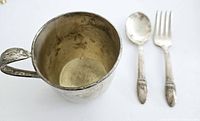 Silver-plated baby cup with fork and spoon displayed on white background showing overall size and condition.