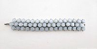 Full view of blue Lucite bracelet laid flat on white background showing three rows of rounded stones and clasp at one end.