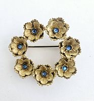Brooch front view showing eight flower motifs with blue centers