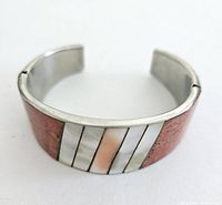 Front view of the vintage cuff bracelet showing inlaid shell segments and silver band with a broken corner.