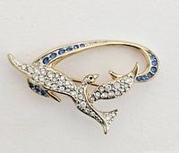 Front view of vintage Swarovski crystal brooch in dove shape with clear and blue crystals on gold-tone metal.