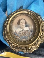 Front view of the oval portrait showing a woman in 19th century style attire, with a gold ornamental frame.