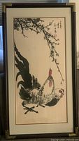 Framed Chinese watercolour painting featuring a black and white rooster beneath a flowering branch, with Chinese calligraphy and red stamps on the upper right.