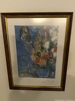 Full view of the signed Marc Chagall print in a wood and gold frame with white matting.