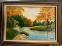 Framed oil painting on canvas depicting an autumn landscape with trees showing autumn colors, a river flowing through grassy banks, and a blue sky with clouds.
