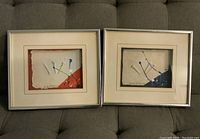 Pair of framed golf-themed art prints by Renwill with abstract golf club designs, on a couch.