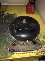 The bell resting on a yellow surface showing the Bevin mark on the metal base and chain pull ring detail.